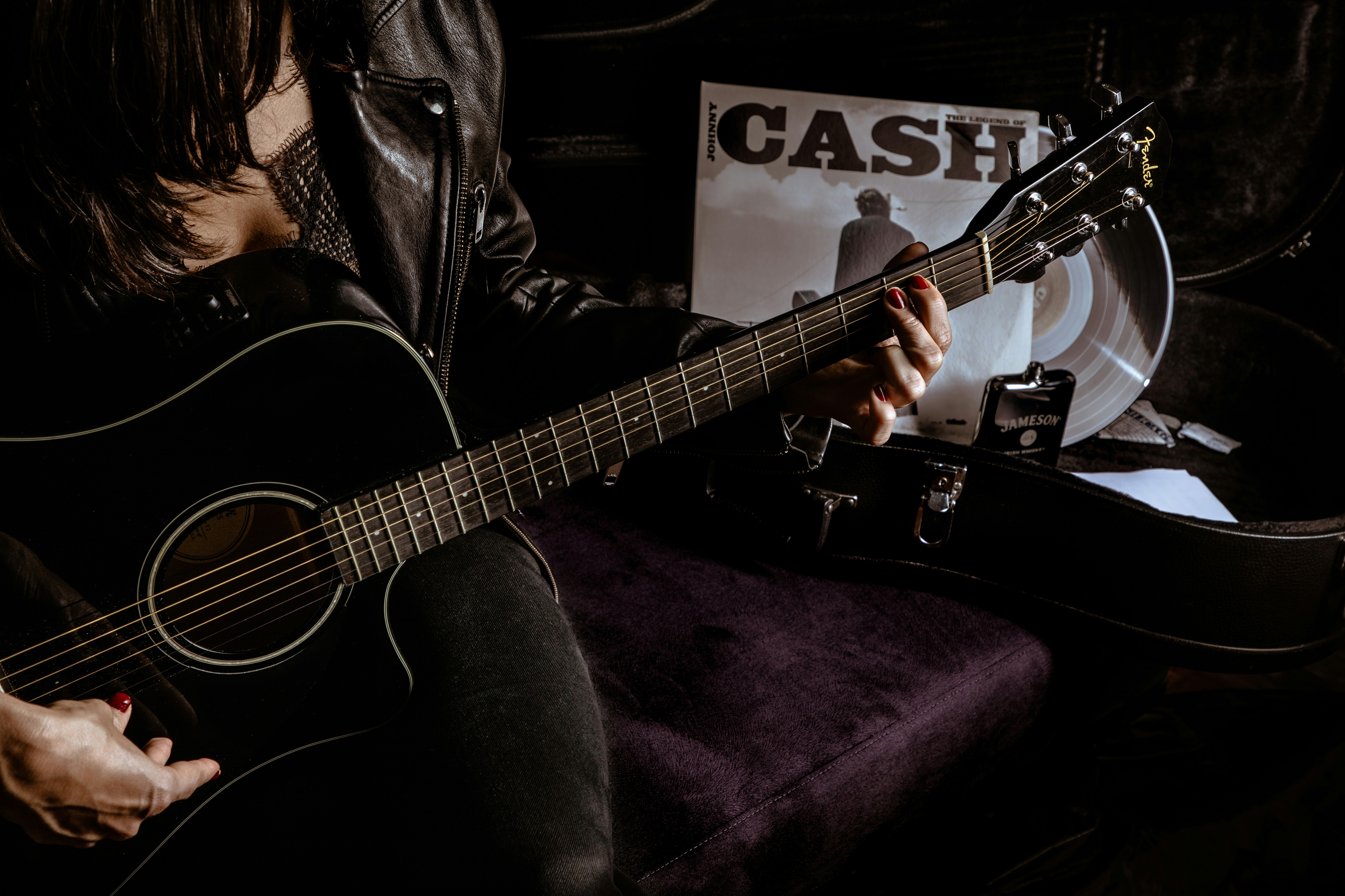 man in black leather jacket playing acoustic guitar
